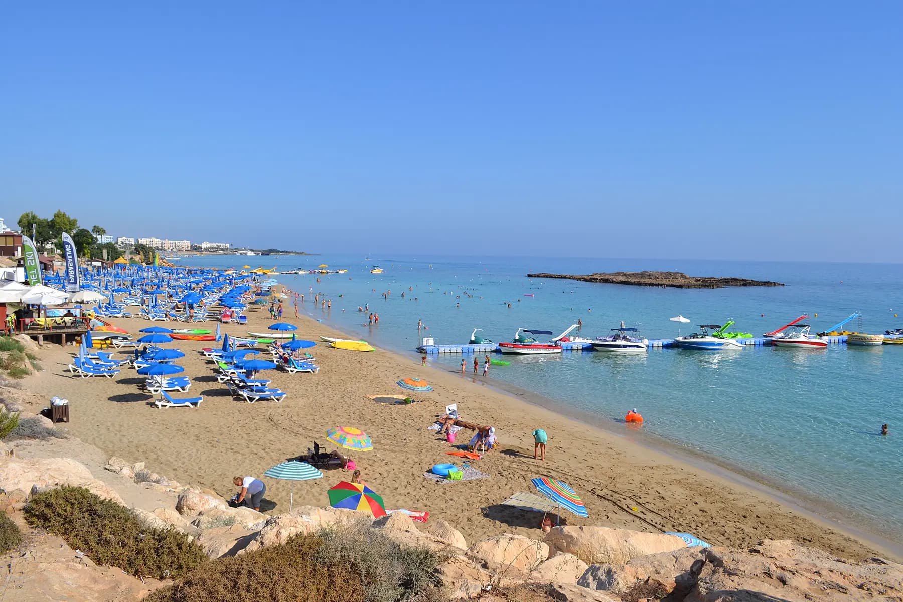 Doğu Kıbrıs kumsali, turkuaz deniz ve sahil şemsiyeleri